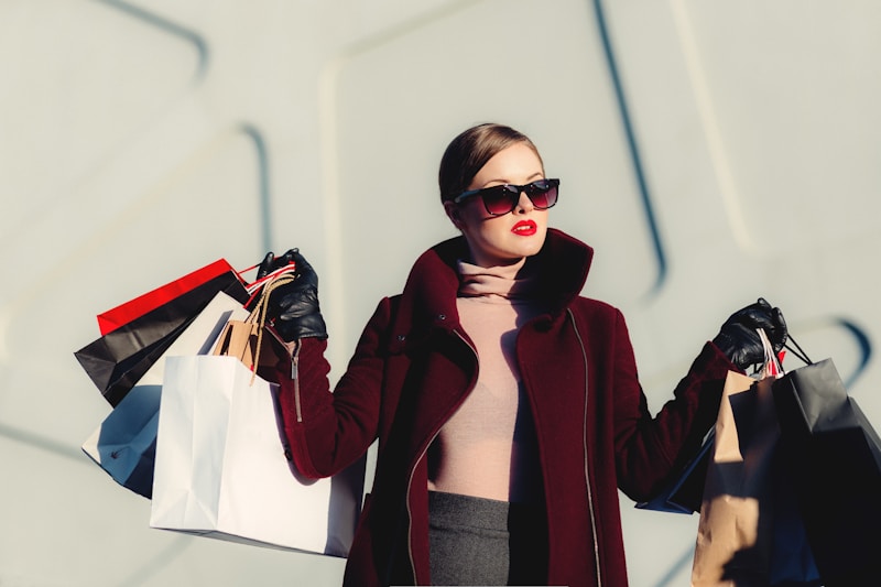 A fashion influencer outside posing with shopping bags while holding a smartphone displaying an Awin profile.