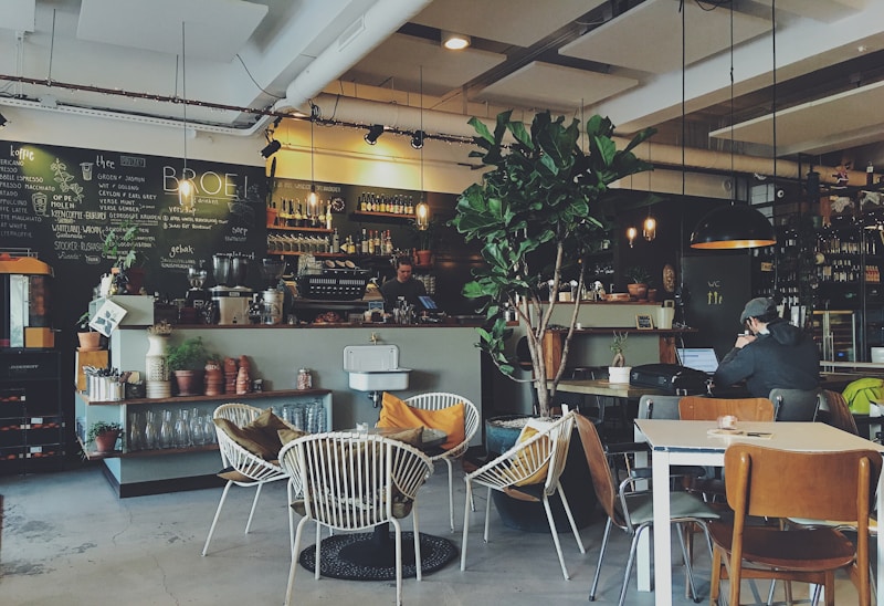 A remote worker working on a laptop inside a bright cafe, browsing DailyRemote.