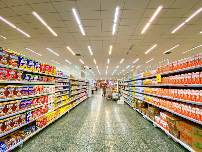 A clean supermarket produce aisle with fresh vegetables and fruits stacked neatly.