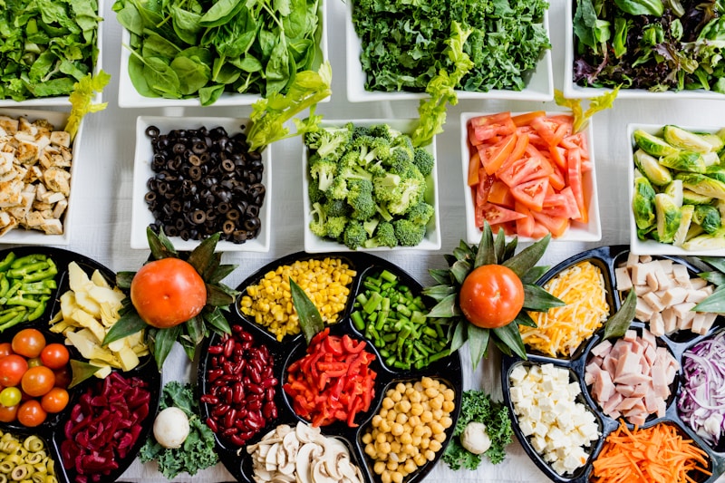 A flat-lay view of seven glass meal prep containers filled with chicken, rice, and green vegetables.