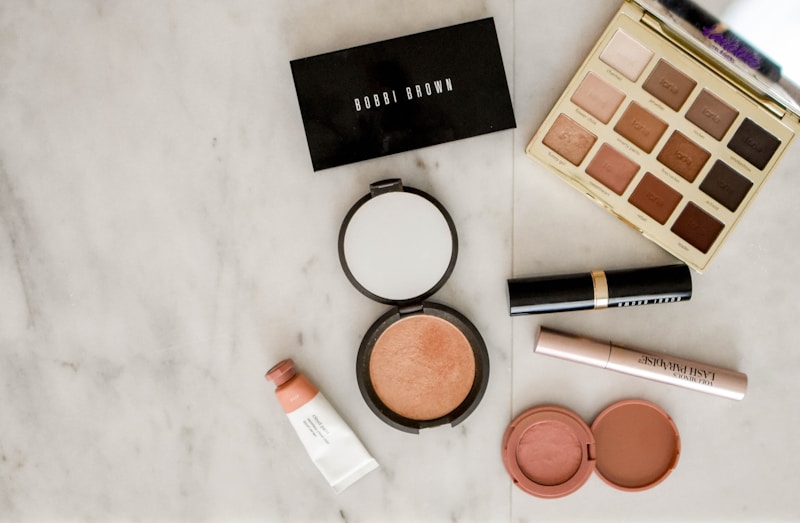 A premium cosmetics flat-lay featuring a smartphone displaying a Rakuten Advertising merchant dashboard.