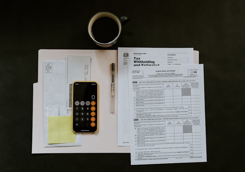 A hand writing monthly budget categories in a financial planner notebook next to a cup of coffee.