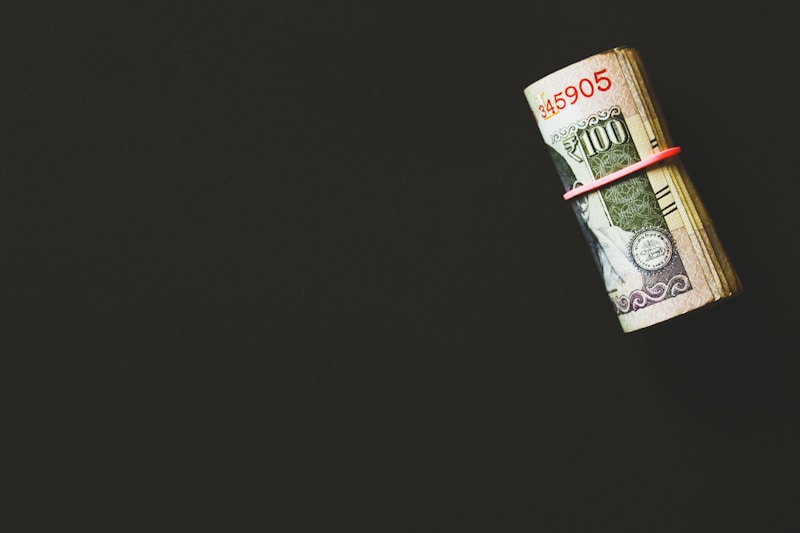 A glass savings jar filled with coins and cash labeled for emergency funds.