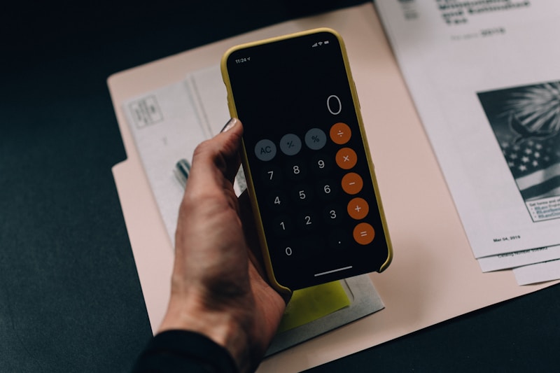 A financial planning folder, calculator, and notebook on a desk for evaluating expenses.
